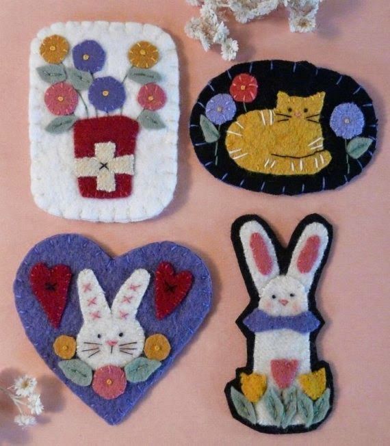 four felt easter bunnies are arranged on a pink surface with flowers and cats in the background