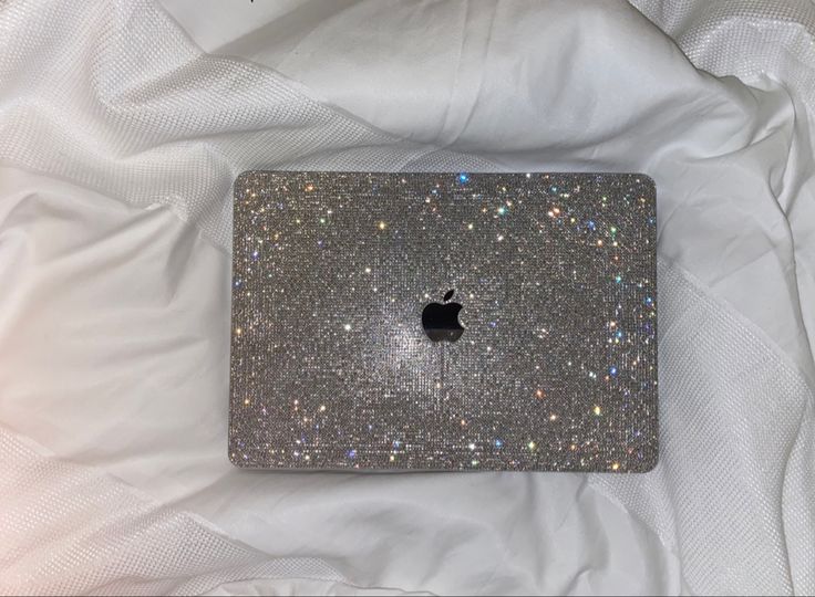 an apple laptop computer sitting on top of a white bed covered in glitters and stars