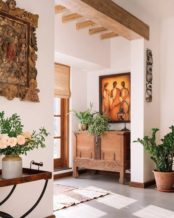 a living room with potted plants and a painting hanging on the wall above it