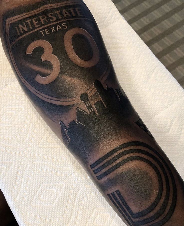 a man's arm with an interstate sign tattoo on it and the number thirty