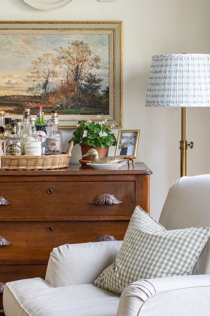 a living room filled with furniture and a painting on the wall above it's dresser