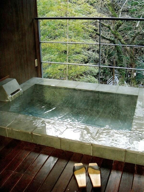 an indoor jacuzzi tub with wooden flooring and wood walls, overlooking the woods