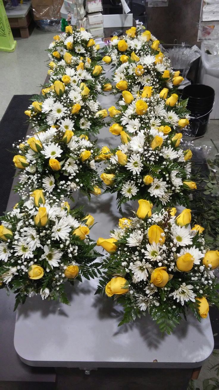 yellow and white flowers are arranged in the shape of a triangle on a table top