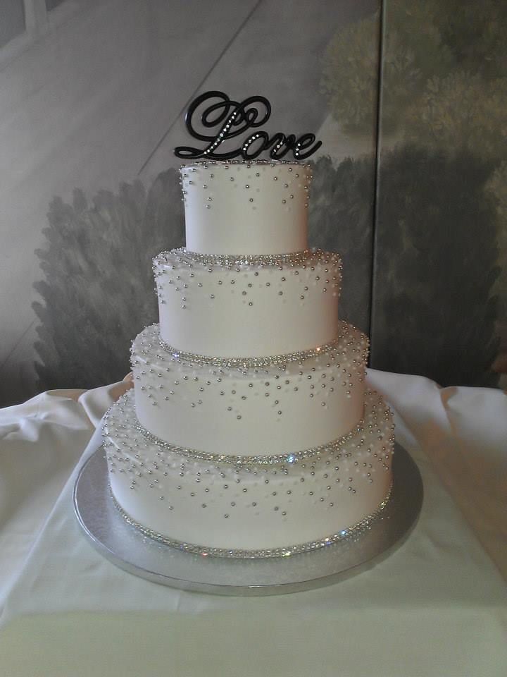 a three tiered wedding cake with white frosting and beaded decorations on top