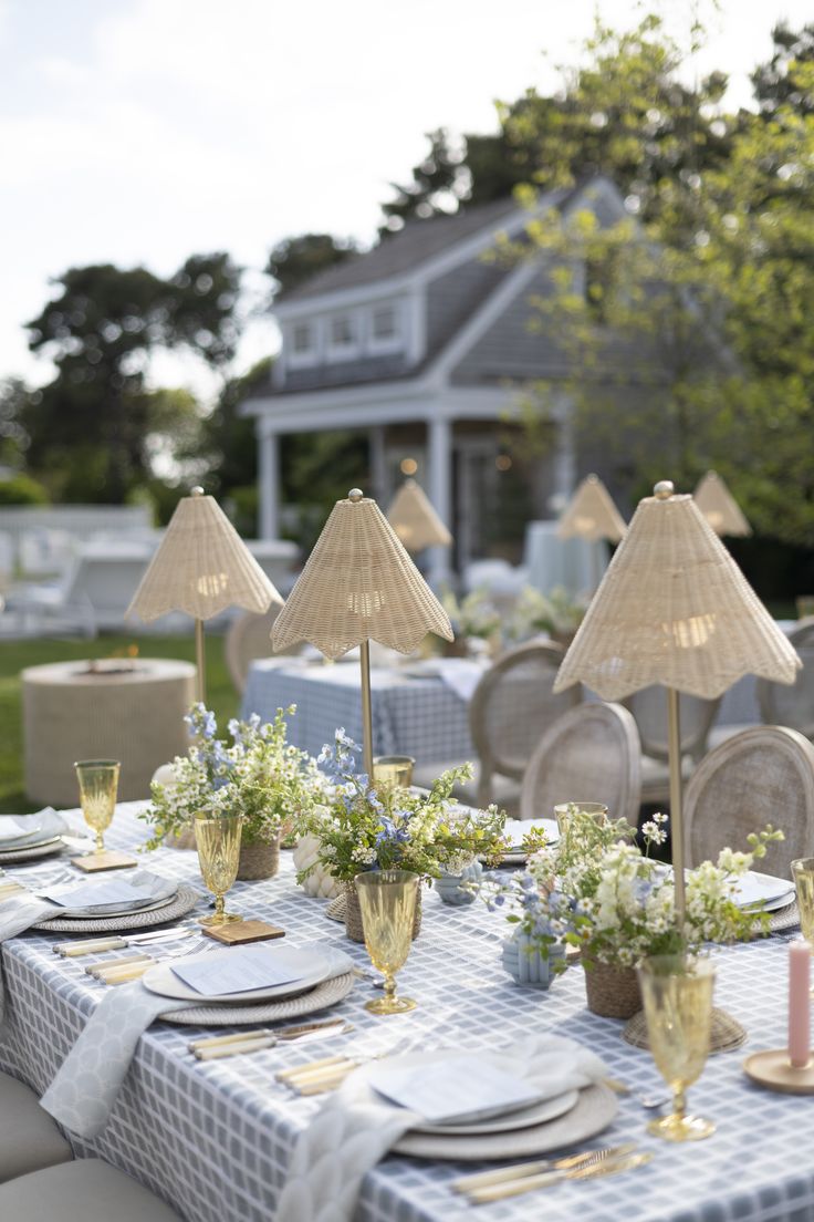 a table set up with place settings and flowers in vases on the tables outside