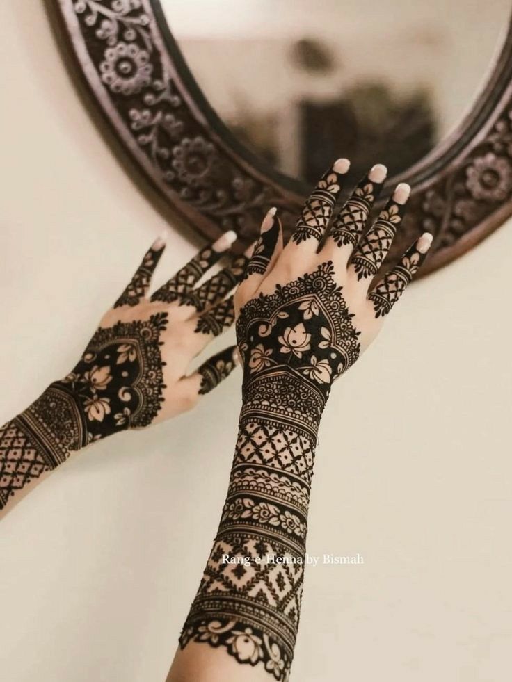 a woman's hands with hennap on her arm and the reflection of a mirror