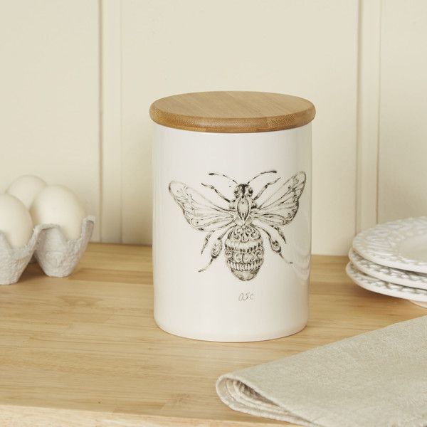 a white canister sitting on top of a wooden shelf next to plates and napkins