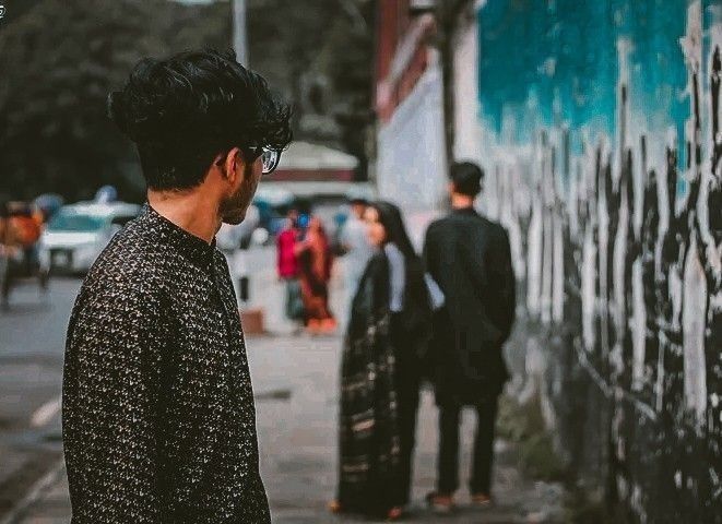 a man standing in front of a wall with graffiti on it and people walking by