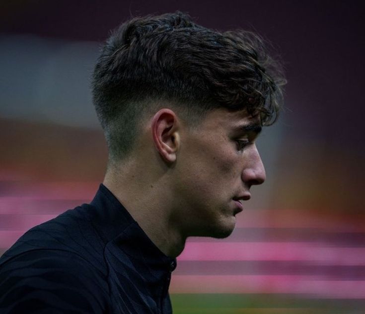 a close up of a young man wearing a black shirt and looking off into the distance