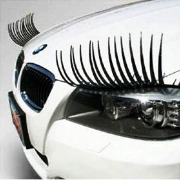 the front end of a white car with black eyelashes on it