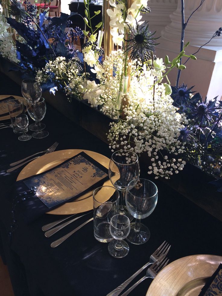 the table is set with silverware, plates and flowers in vases on it