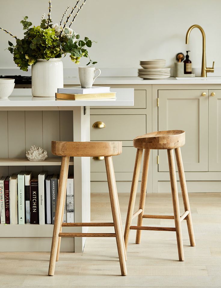 two wooden stools sitting in front of a kitchen island with bookshelves on it