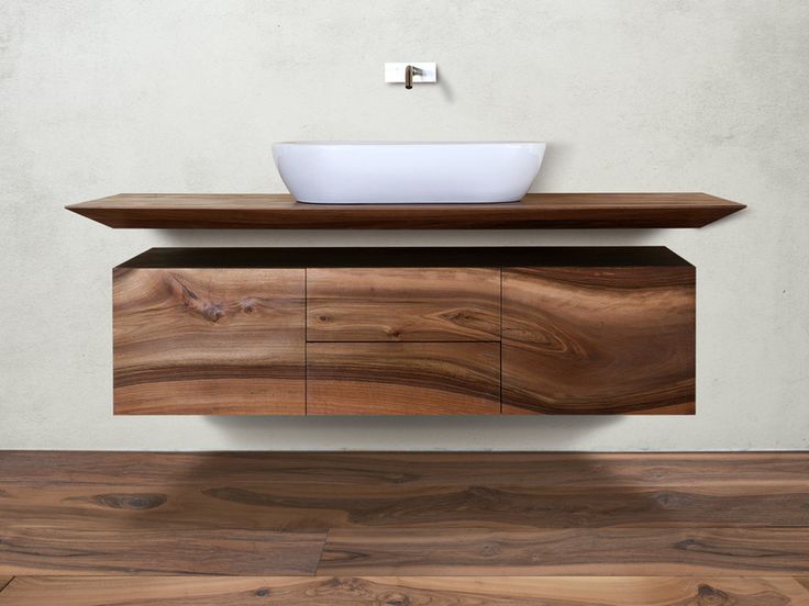 a bathroom sink sitting on top of a wooden counter next to a wall mounted faucet