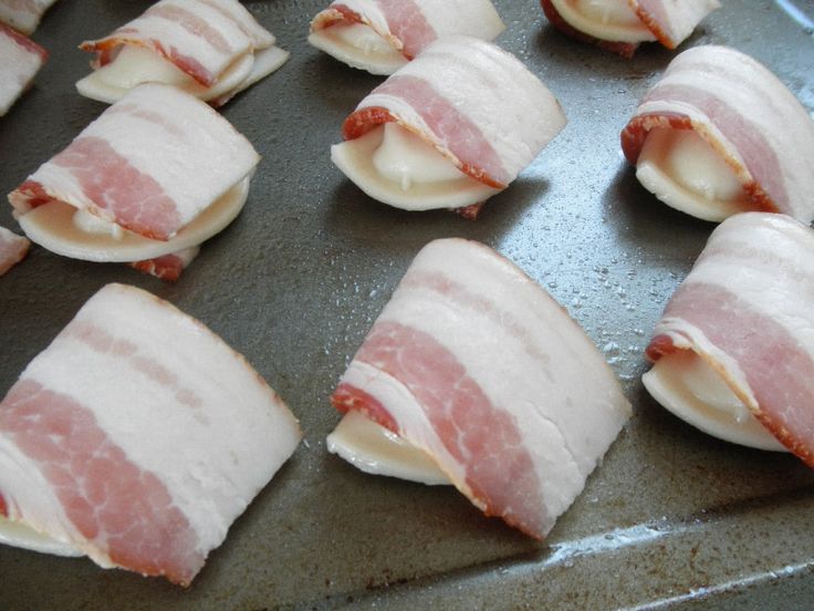 bacon wrapped in cheese on top of a baking sheet