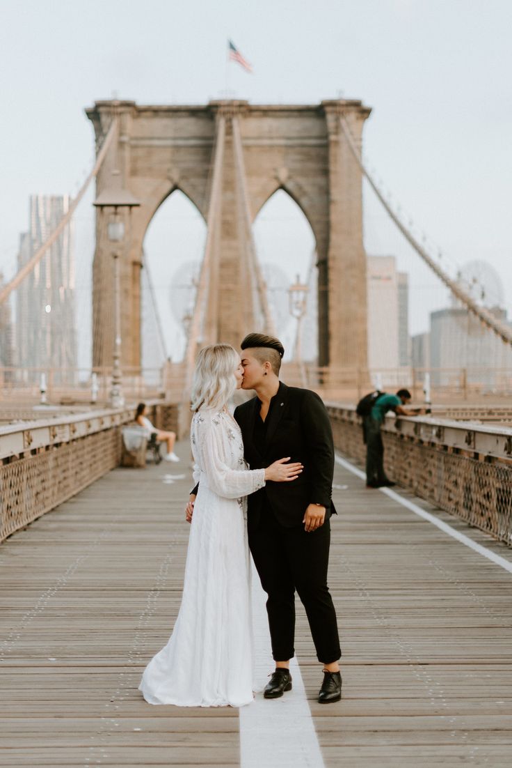 a bride and groom kissing on the brooklyn bridge