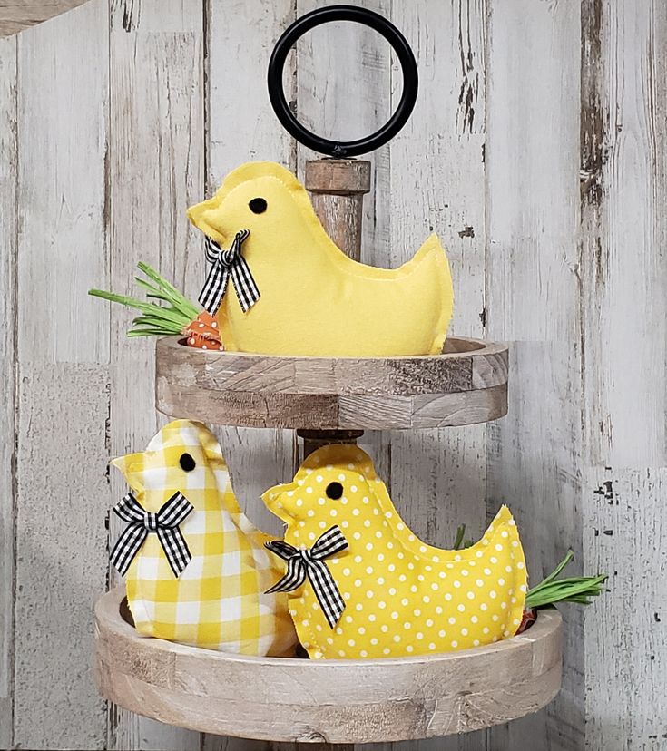 three yellow chickens sitting on top of a wooden shelf