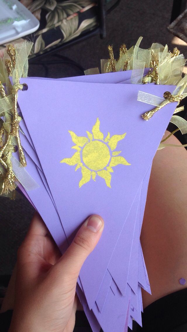 a person holding up some purple paper with yellow sun on it and gold foil around the edges