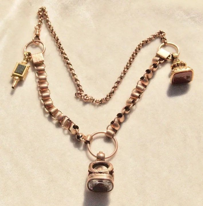 What a find! This necklace was once a watch chain (or a couple of watch chains), that someone at some point has converted to a wonderful statement necklace. It is marked 14k on the swivel clasp and all parts are 14k or higher. The fobs are Georgian and early Victorian and the watch key is Georgian. The fobs have a foiled white stone, most likely quartz, a carnelian, and the key has a blood stone and foiled white stone. Necklace length is 19 1/2 inches and this weighs a hefty 44 grams. You can add your own charms of you like, this has a lot of options for wear. Follow me on instagram@jettesjewels. Antique Necklace With Adjustable Chain, Vintage Keepsake Necklace With Adjustable Chain, Antique Watch Chain Necklace, Antique Gold Pocket Watch With Vintage Charm, Victorian Self-winding Collectible Pocket Watch, Watch Chain, White Stone, Gold Watch, Charm Necklace