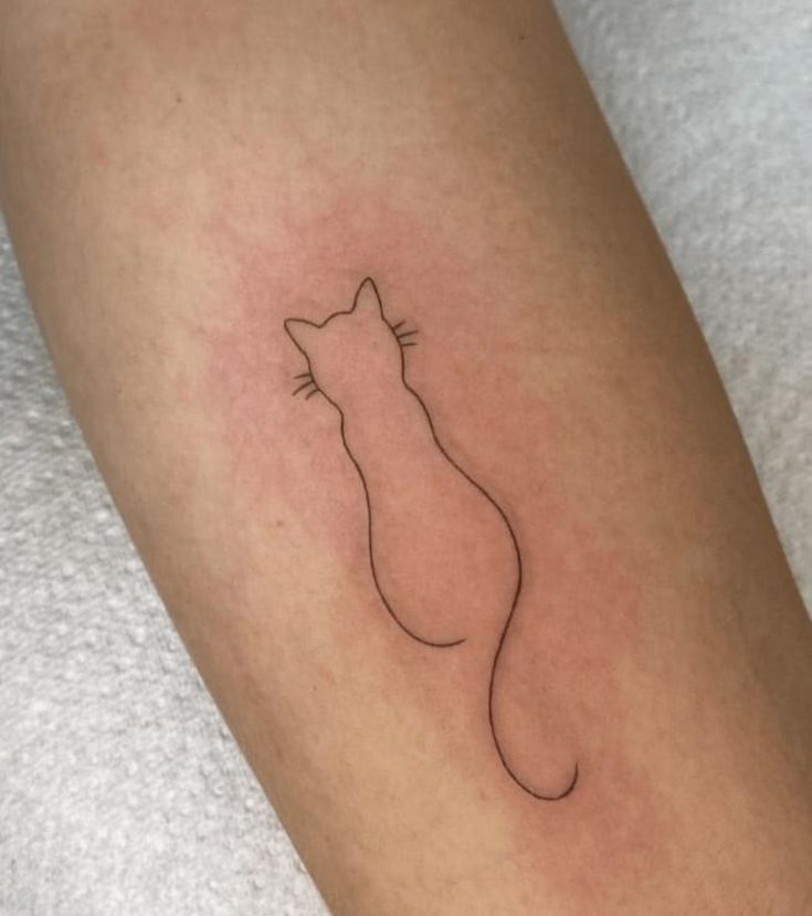 a small cat tattoo on the left leg, with an outline of a cat's head