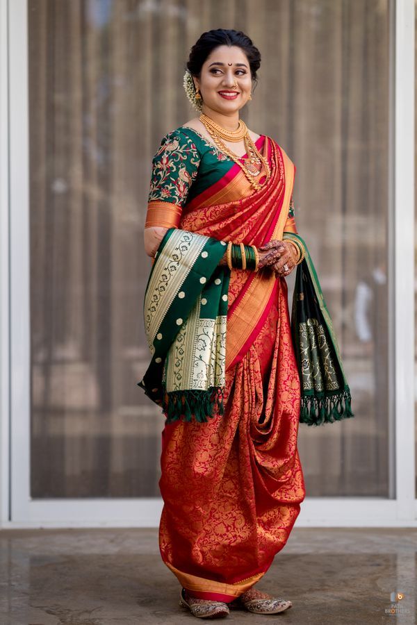 a woman in an orange and green sari is standing by a glass door with her hands on her hips