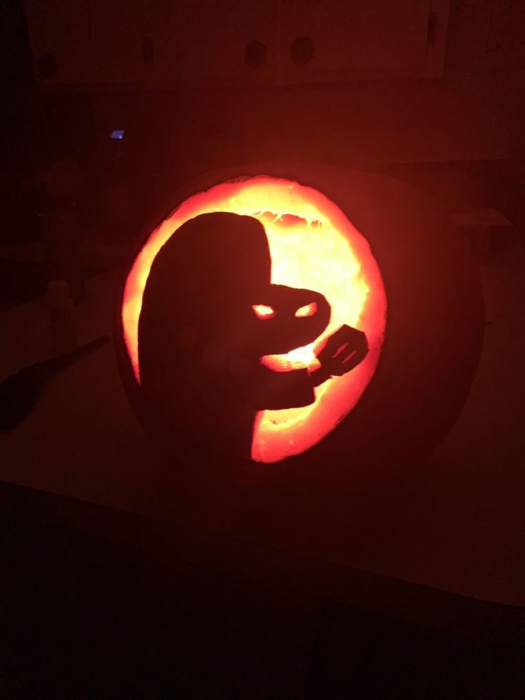 a carved pumpkin with the shape of a person's head in front of it