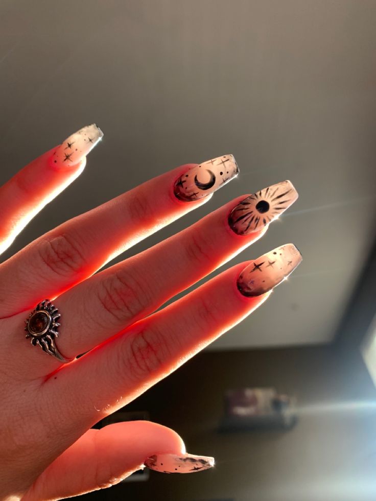 Boho witchy space nails with sun moon and planets. Black nail art on light pink nails Witchy Moon Nails, Boho Nails Aesthetic, Cute Moon Nails, Nails With The Moon, Moon Art Nails, Witchy Acrylic Nail Designs, Nails For Witches, Moon Nail Art Simple, New Moon Nails