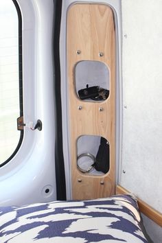 the interior of a camper with a bed and storage compartment on it's side