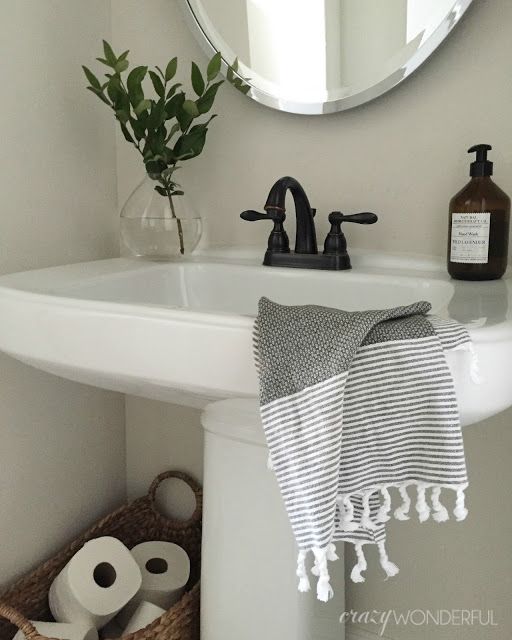 a white sink sitting under a bathroom mirror next to a towel and soap dispenser