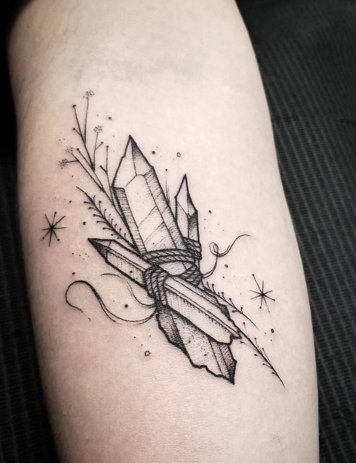 a black and white photo of a diamond tattoo on the arm with stars around it