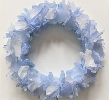 a blue and white wreath made out of tissue paper on top of a table next to a wall