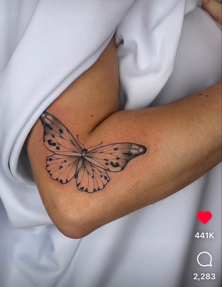 a woman's arm with a small butterfly tattoo on the left side of her arm