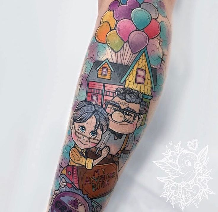 a woman's leg with tattoos on it that has balloons and houses in the background