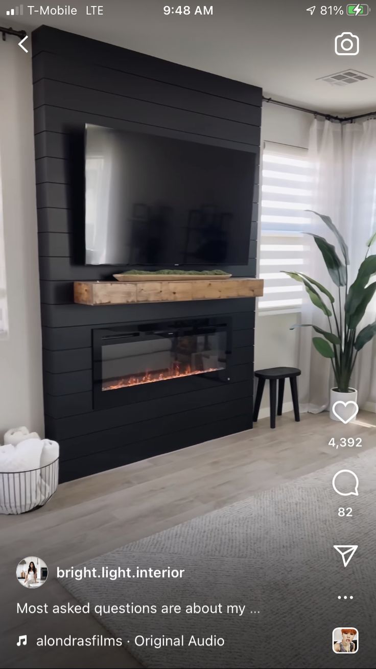 a living room with a large television mounted on the wall and a fire place in front of it