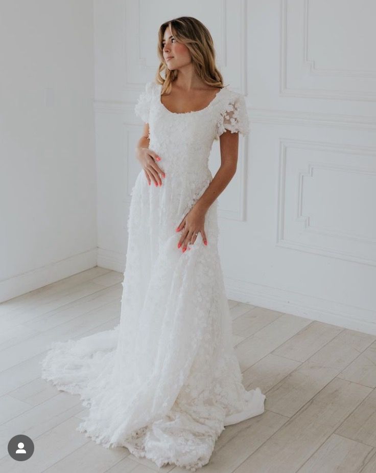 a woman in a white wedding dress posing for the camera with her hands on her hips