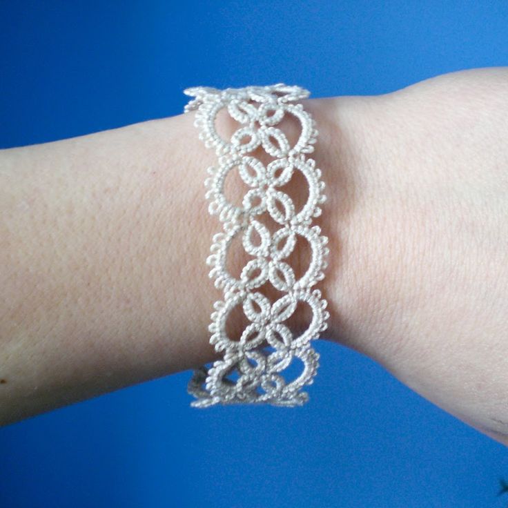 a woman's arm with a white bracelet on her left wrist and a blue background