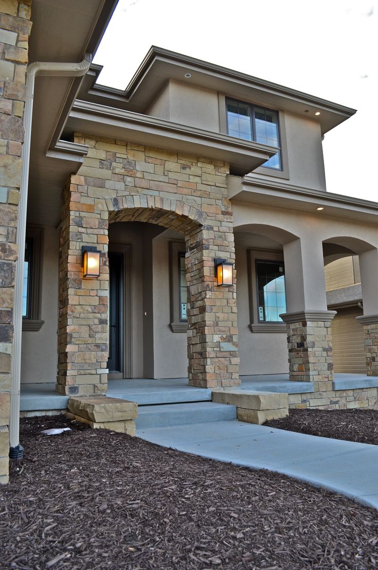 a house that has some lights on in front of the door and side of the house