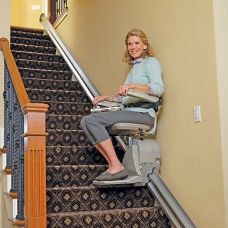 a woman sitting on top of an escalator next to a stair case in a house