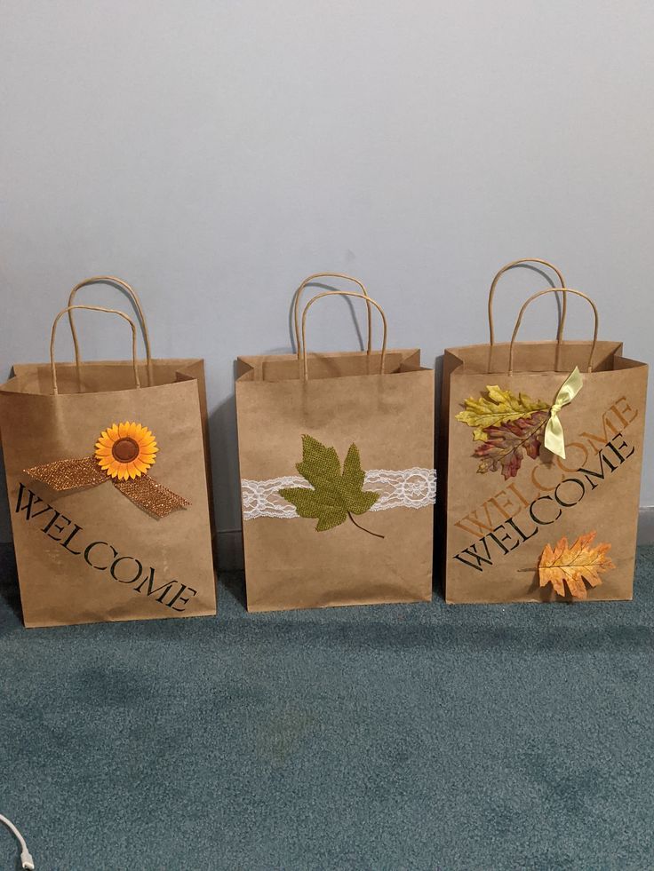 three brown paper bags with fall leaves on them and the words welcome to us are placed next to each other