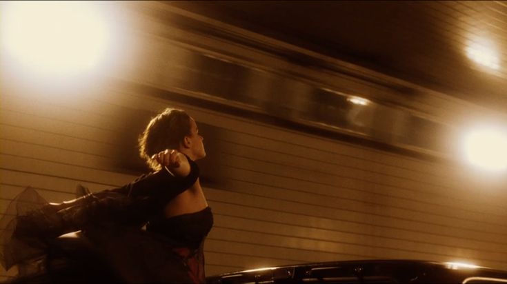 a woman talking on her cell phone while standing next to a parked car at night