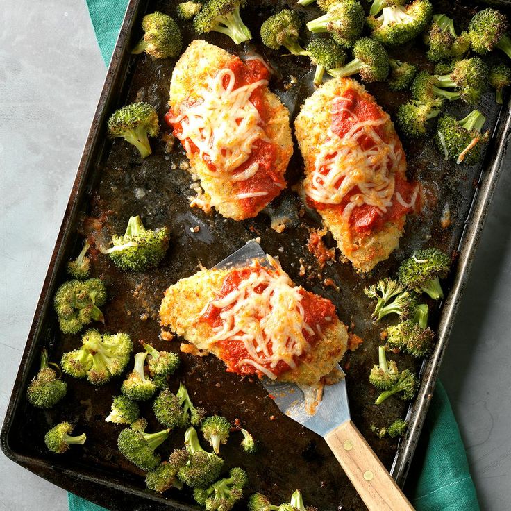 broccoli covered in cheese and sauce on a baking sheet with a spatula