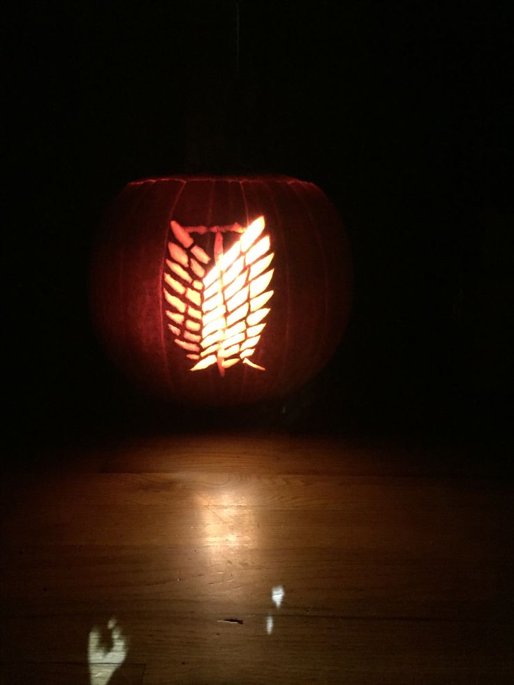 a carved pumpkin sitting on top of a wooden floor in the dark with light shining through it