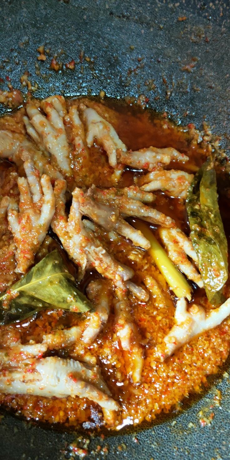 some food is being cooked in a wok on the stove top with sauce and seasonings