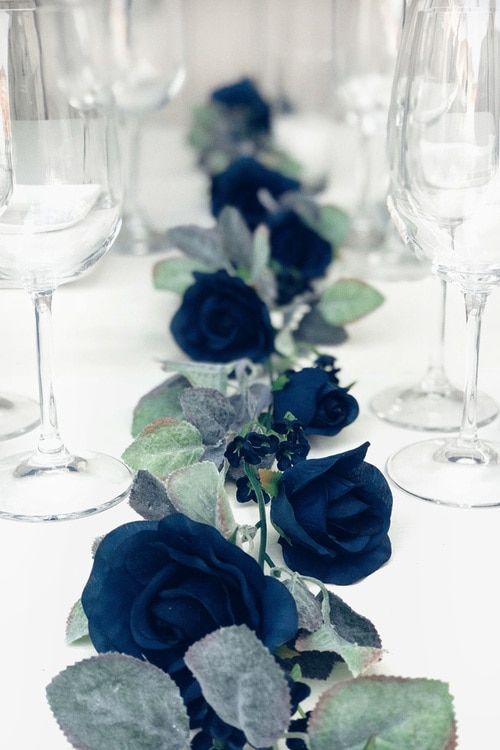 there are many wine glasses on the table with blue flowers in them and one is empty