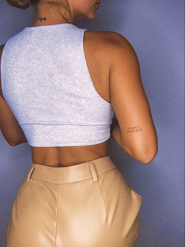 a woman with her back to the camera, wearing tan pants and a white crop top