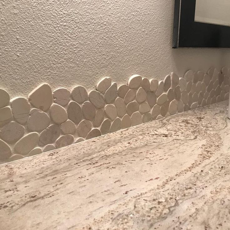 a bathroom counter with rocks on it and a mirror in the corner next to it