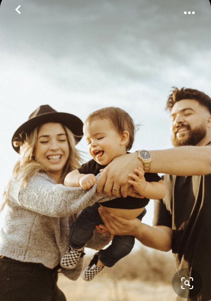 a man and woman holding a baby in their arms