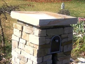 a small brick oven sitting in the middle of a yard next to some grass and flowers