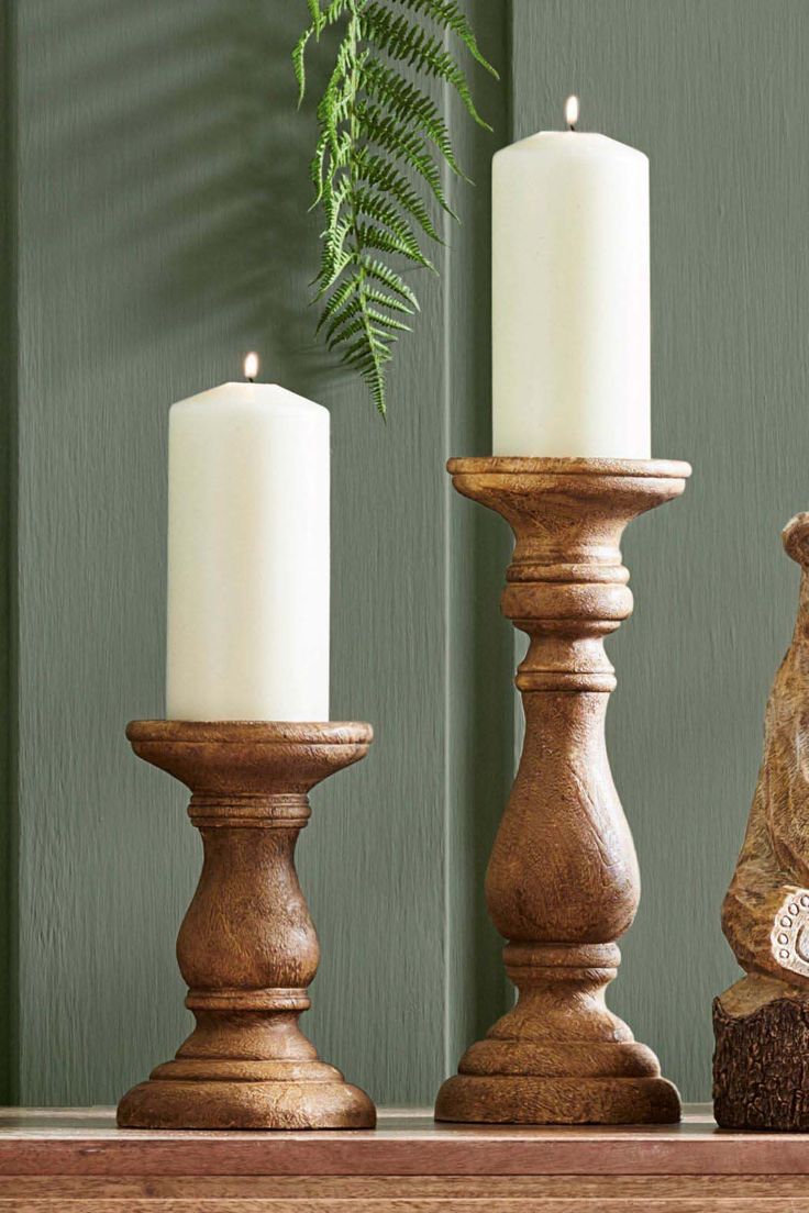 three candles sitting on top of a wooden mantle