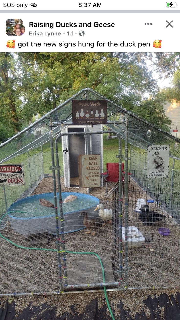 a small caged in area with signs on the sides and an animal enclosure behind it