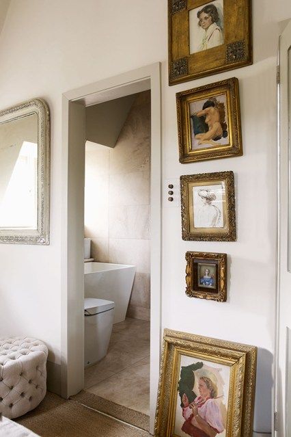 a bathroom with pictures on the wall and framed photos hanging on the wall next to the toilet